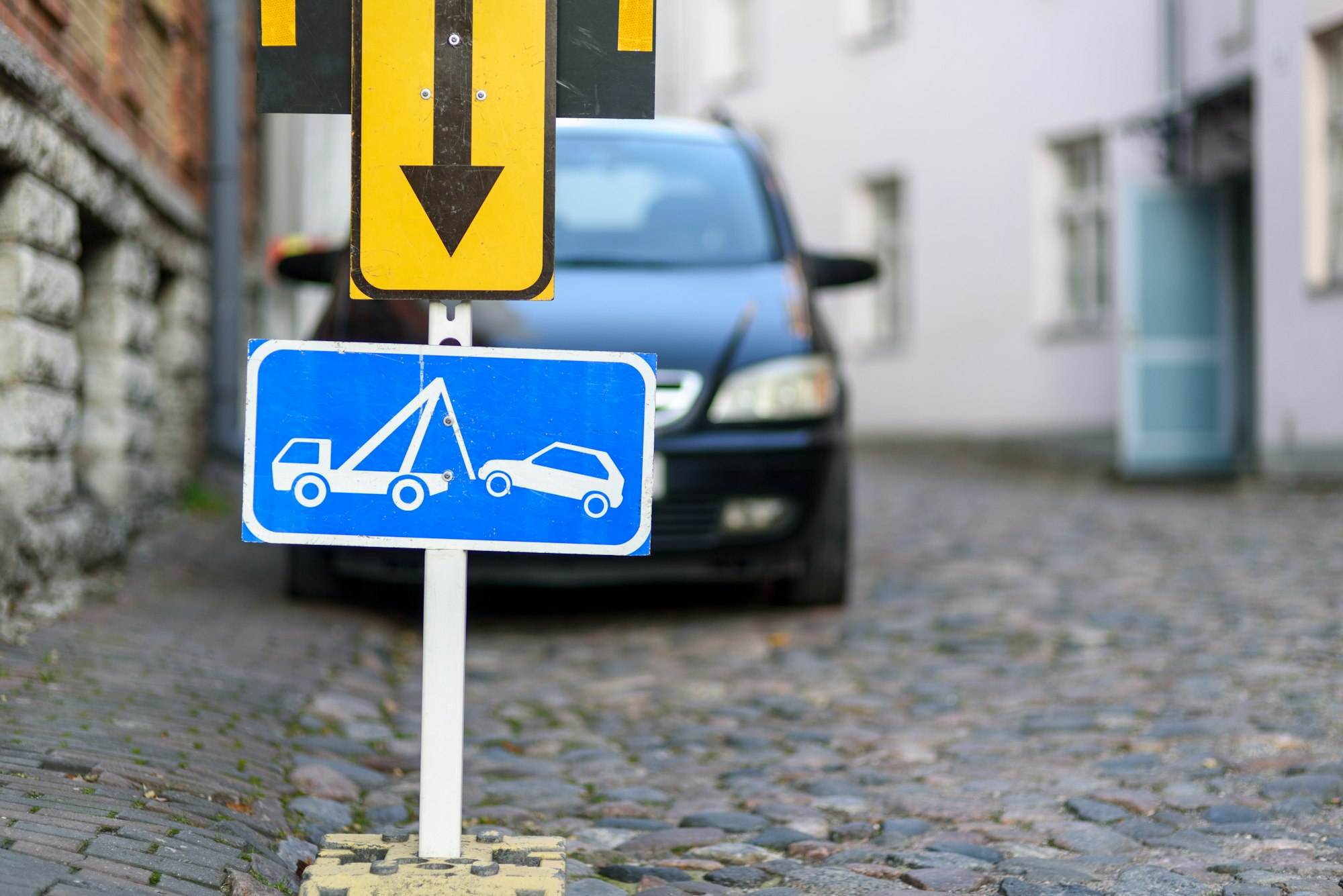 Tow away zone road sign with car on background